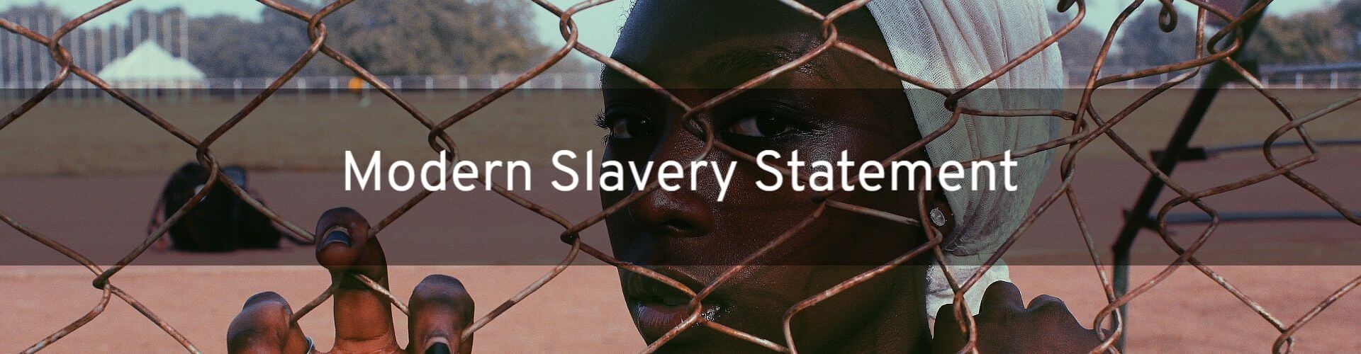 Title Image. Picture of a sad looking African woman looking through a wire fence.