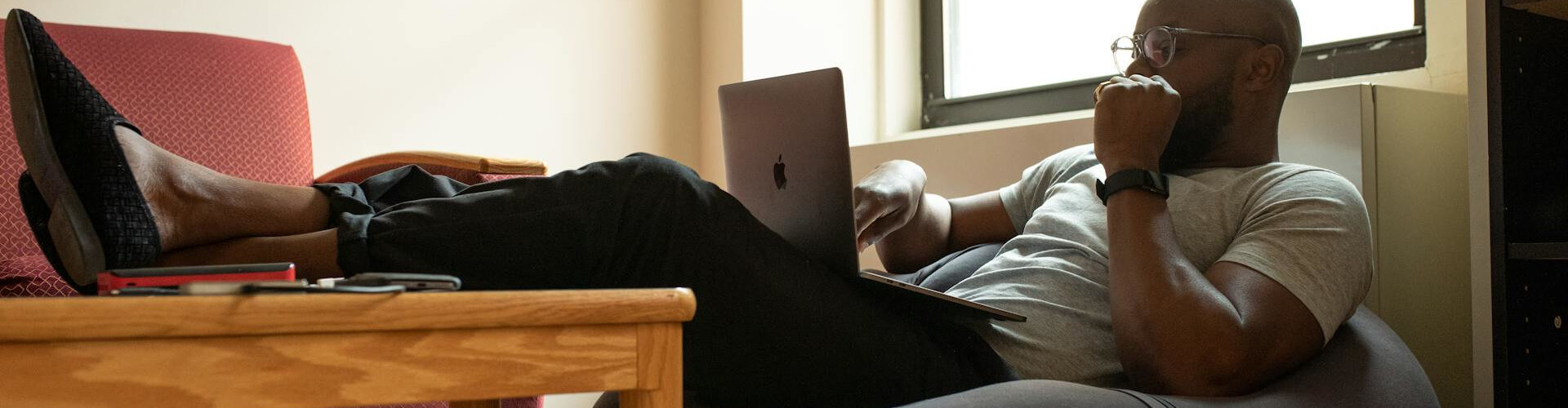 Remote employee reading a digital newsletter on a laptop in a casual setting.